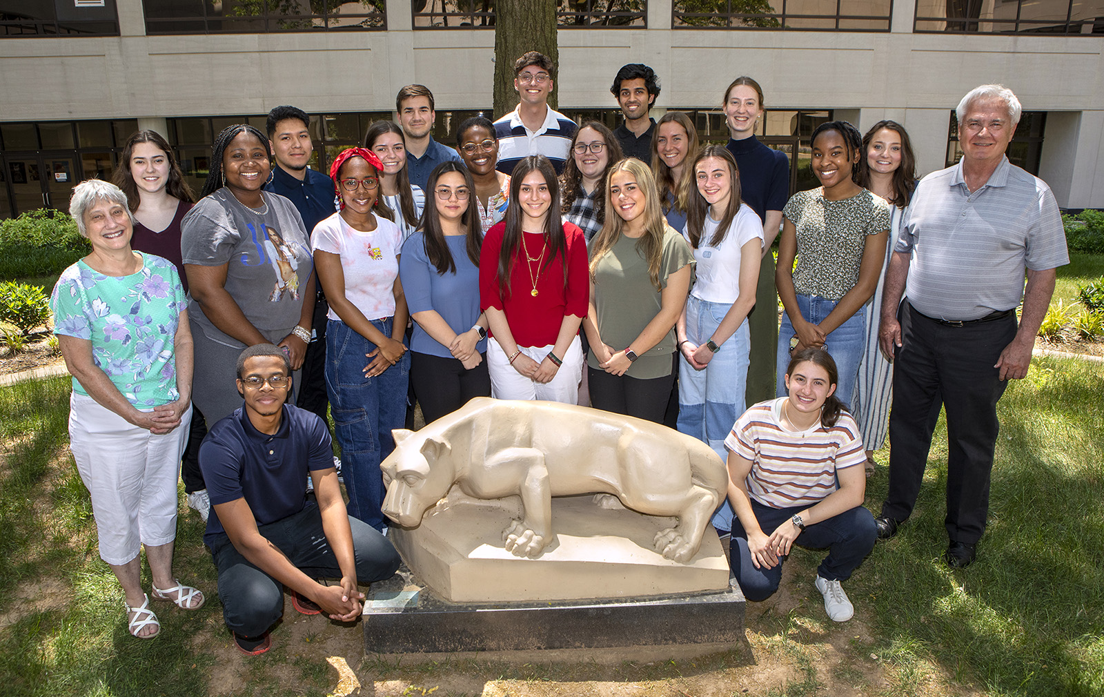A group of 23 people pose around the Nittany Lion statue in the Penn State College of Medicine courtyard. 