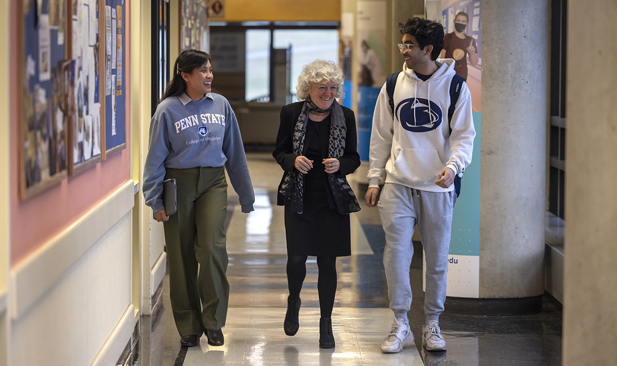 Dr. Erica Friedma, vice dean for Educational Affairs for Penn State College of Medicine, interacts with students Natalie Hearty, left, and Akhil Bolisetti, as they walk down the hallway with Friedman in the middle.