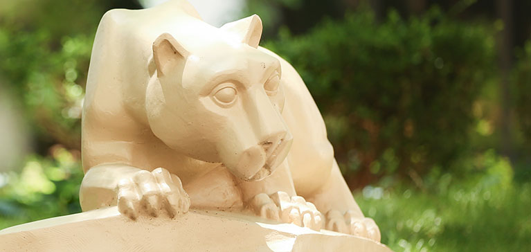 The Penn State College of Medicine Nittany Lion statue is seen surrounded by plants in the central courtyard of the College.