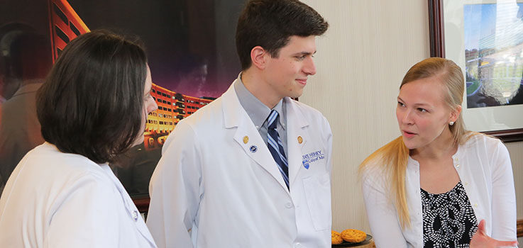 Three Family and Community Medicine students in the Family Medicine Accelerated Program at Penn State, which offers three years of medical school and three years of residency in an accelerated program, are seen having a conversation during the program entrance signing in 2016.