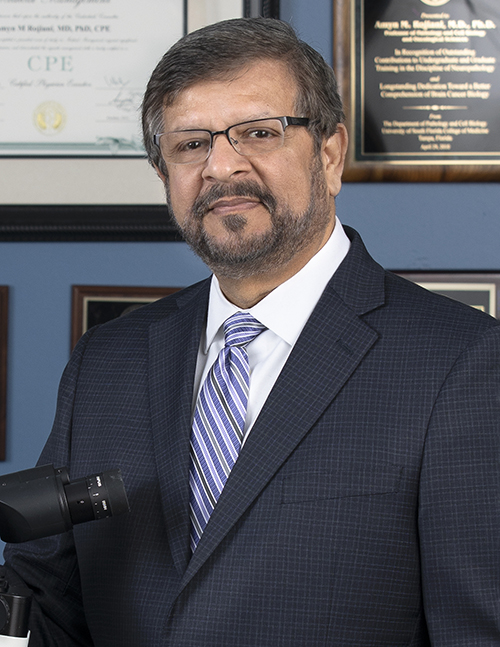 Amyn Rojiani, MD, is the Interim Chair, Department of Pathology and Laboratory Medicine. He is pictured in a white medical coat against a blue background. 