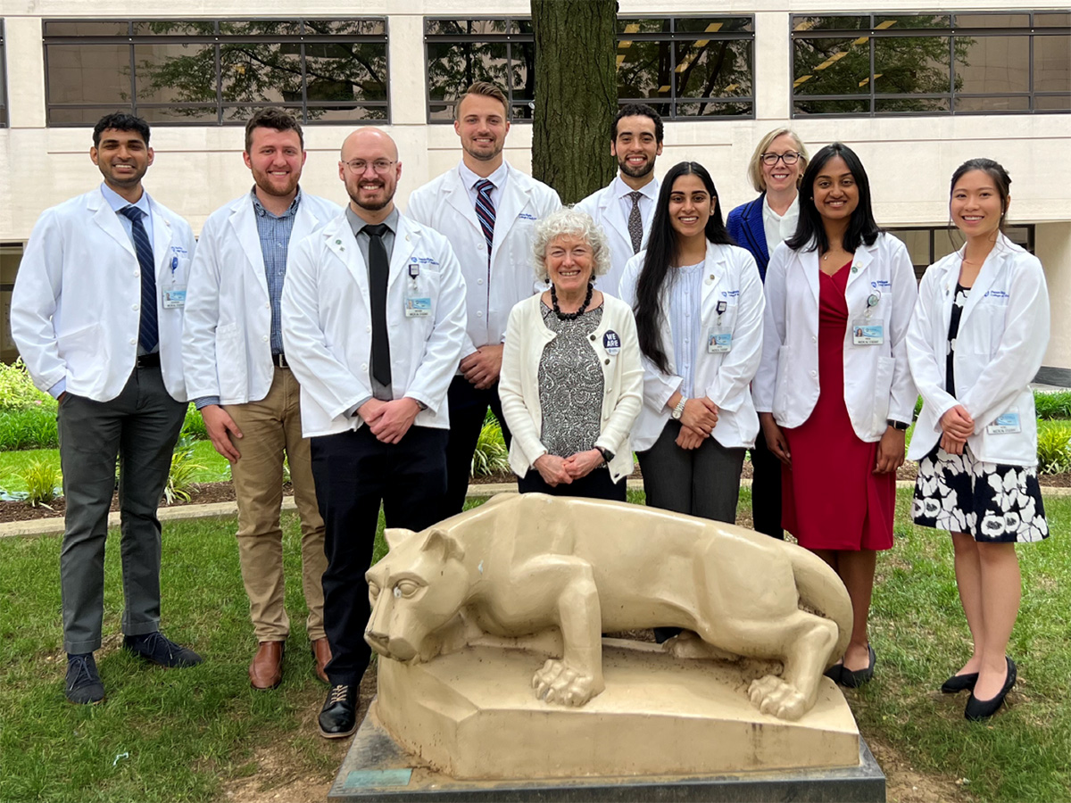 Ten people stand behind a Nittany Lion statue in the courtyard of Penn State College of Medicine.