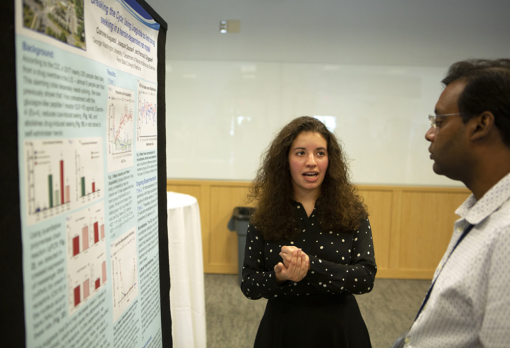 A photo of Connie Augusto presenting her research to Anirban Paul, an assistant professor of neural and behavioral sciences.