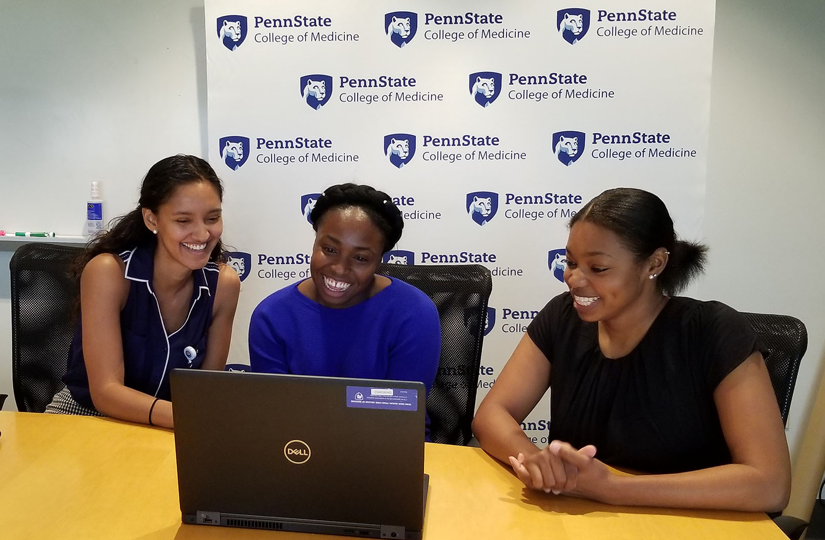 Medical school students from diverse backgrounds looking at a laptop and smiling during a virtual meeting with undergraduate students participating in the Talks with Docs program.