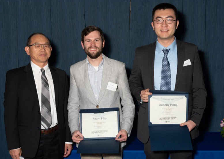 Dr. Jianming Hu, left, stands next to Ender's Award recipients Adam Fike and Xupeng Hong, who are holding their awards in front of them. 