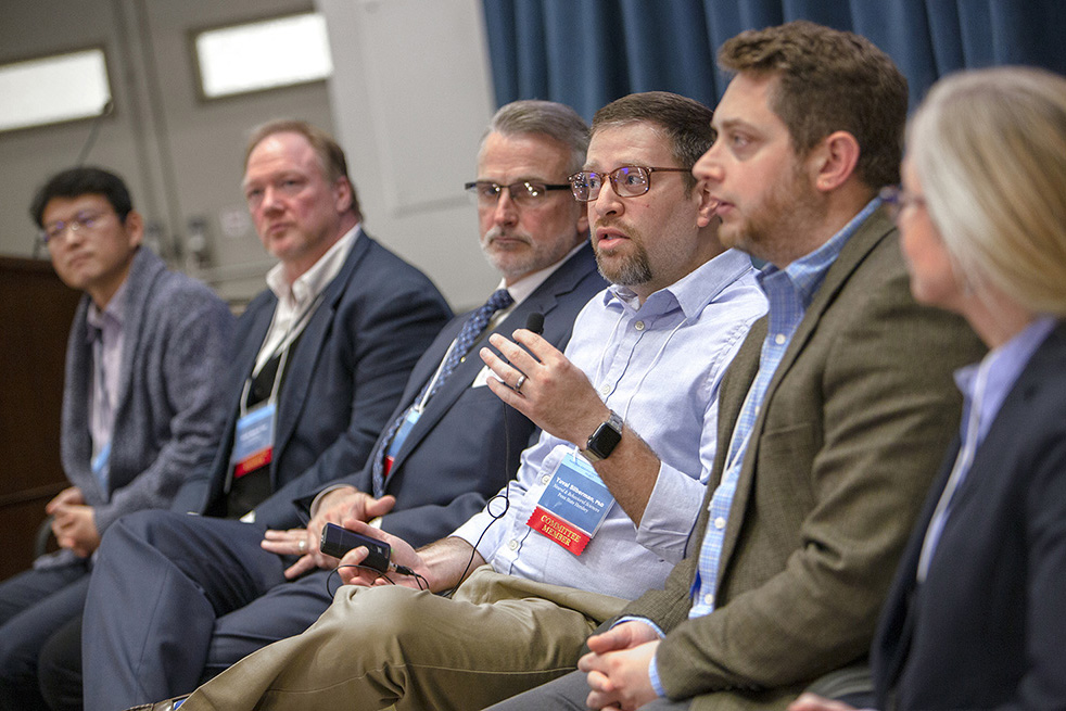 Yuval Silberman, third from the right in a panel of 6 people seated in a row, speaks during the 2019 addiction symposium.